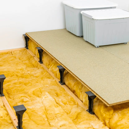 Wooden floor with insulation and metal brackets in a room.